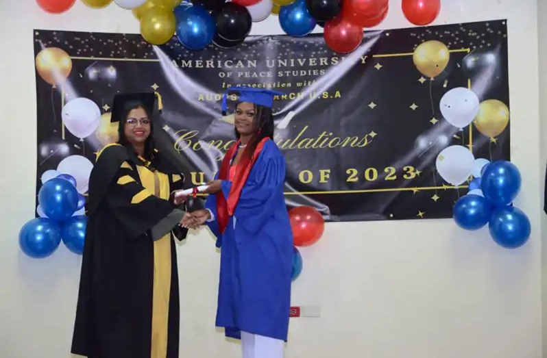 One of the graduates receiving her certificate from a lecturer at the American University of Peace Studies