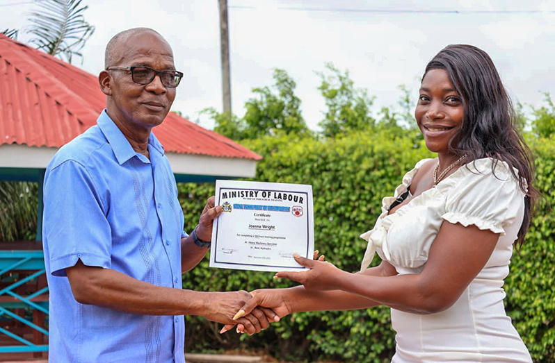 Minister of Labour Joseph Hamilton (left) presents a graduate with her certificate