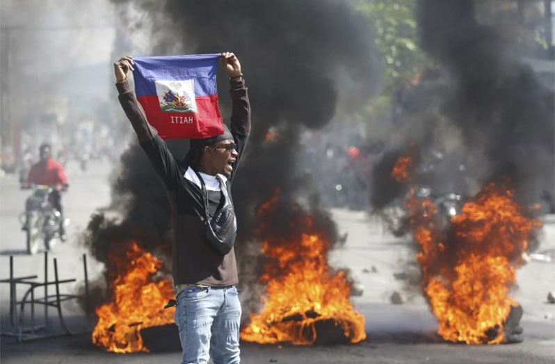 A demonstrator holds up a Haitian flag during fiery protests (Source: AP / Odelyn Joseph)