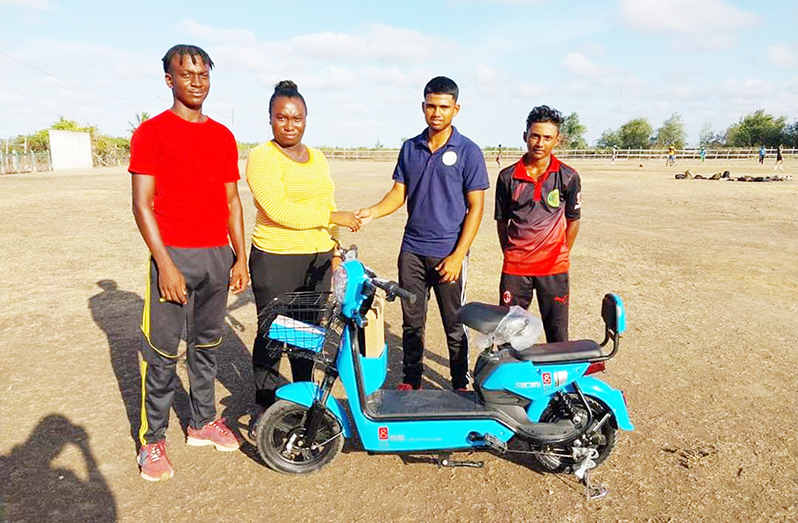 Matthew Pottaya hands over electric bike to Ms. Keisha Marks of Sharon Congregational Church