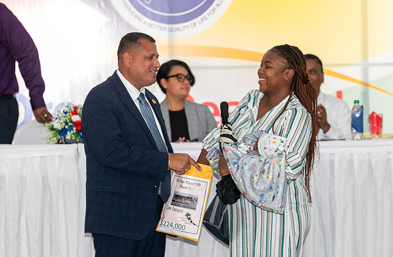 The Minister of Housing and Water, Collin Croal, and one of the allottees pulling her lot number from the envelope (Delano Williams photo)