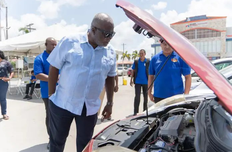 Prime Minister, Brigadier (Ret'd) Mark Phillips examines an electric vehicle (EV) on display during the GEA’s inaugural EV Show and Tell Exhibition at the Amazonia Mall, Providence, held in March 2024. 