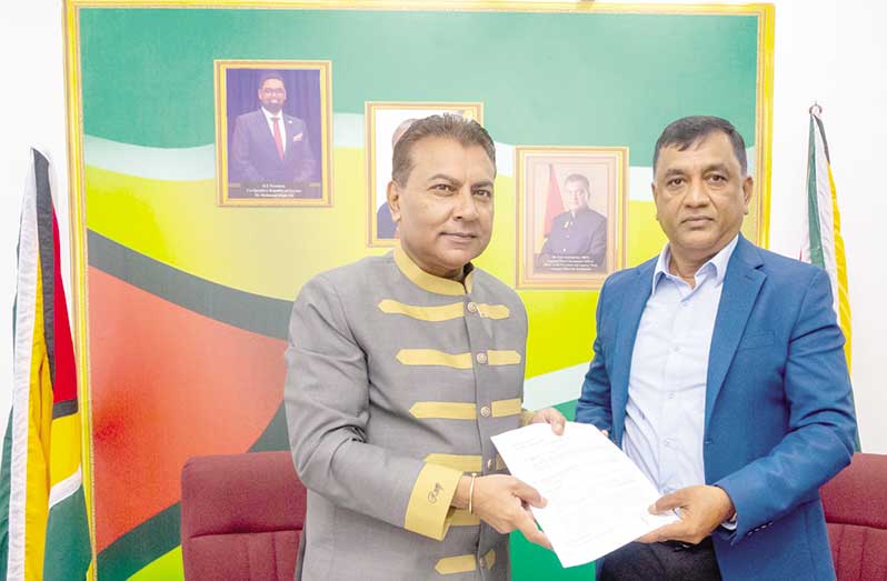 Handing over of the agreement by Dr Peter Ramsaroop, Guyana's Chief Investment Officer and Agency Head of the Guyana Office for Investment to PWSI CEO Mahendra Jettoo