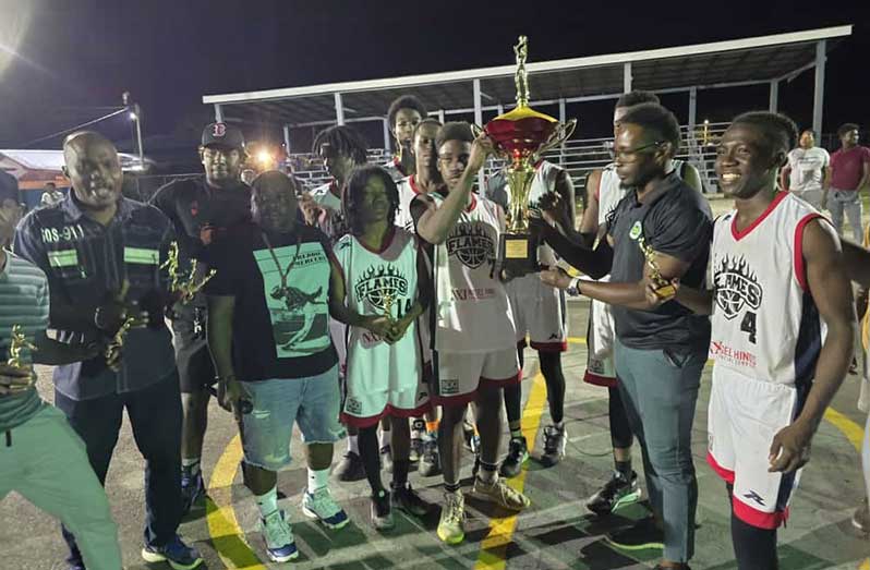 The winners of the Kevin ‘2feet’ Joseph Team 13 U-23 Basketball Final Block 22 Flames collect their trophy from Larry Simon