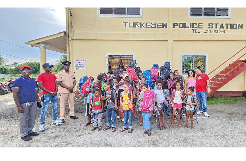 From right: Businessman and gold miner Paul Chow and his wife Rayana Chow and head of the Station Management Committee, Edward Singh (extreme left), followed by Station Sergeant Corwin Adams and Inspector W. Williams with some of the children who received school bags and supplies