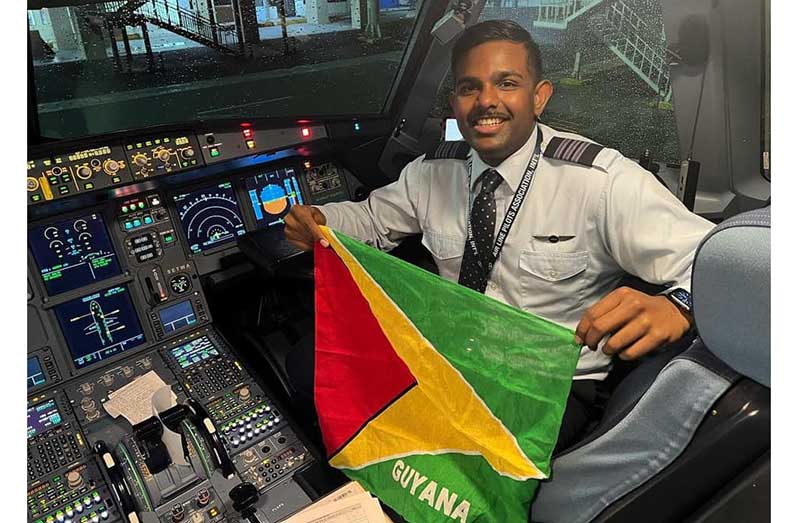 Guyanese-born pilot Antonio Prittipal proudly holds the Guyana flag in the cockpit after landing a commercial flight at CJIA, fulfilling a childhood dream.