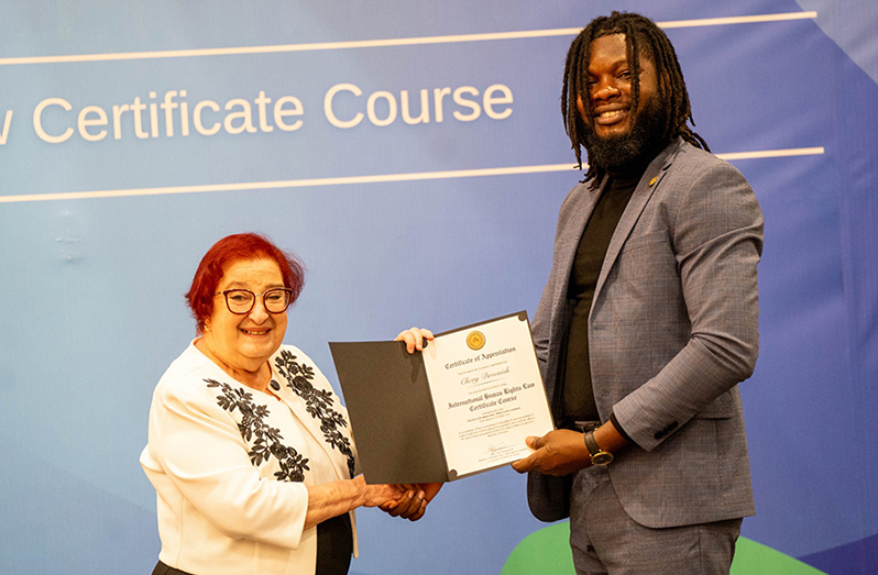 Senior Legal Adviser Chevy Devonish proudly accepts his certificate from Minister Gail Teixeira during the graduation ceremony