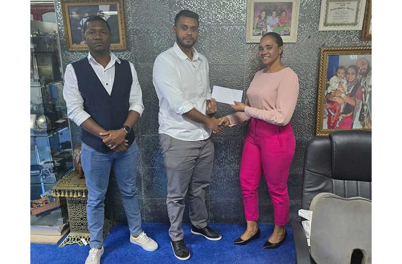 CEO of BK Group of Companies, Kyle Tiwari hands over sponsorship to Bartica Easter Regatta Committee member, Shondel Gilkes in the presence of colleague, Sheldon Kyte