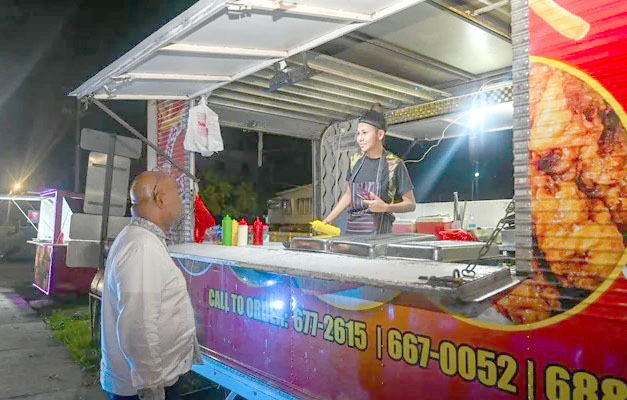 Minister of Public Works, Bishop Juan Edghill, engages a food-truck worker on Friday
