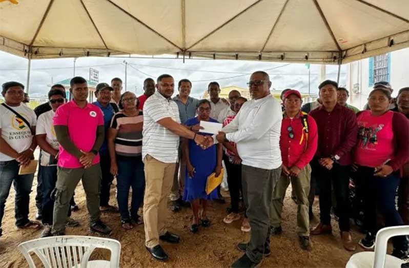 Minister of Natural Resources, Vickram Bharrat, handing over funds to one of the village leaders in Region Nine
