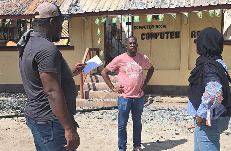 MoE officials outside the fire-ravaged section of the Kwakwani Secondary School. The ministry has assured students, teachers, parents and other stakeholders that arrangements will be put in place to ensure students and teachers are back in the classroom before the end of September (Photo: Ministry of Education/Facebook)