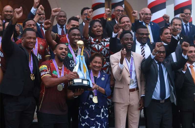 Prime Minister Kamla Persad-Bissessar (centre) holds the CPL trophy with Trinbago Knight Riders captain Nicholas Pooran (second left). Also pictured are World Champion javelin thrower Keshorn Walcott (left) and silver medallist Jereem Richards (third right)