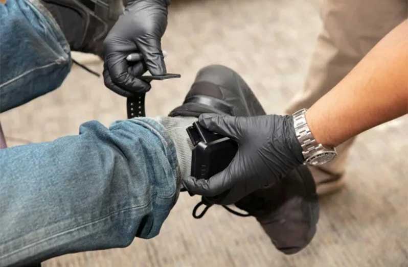 An ankle-monitoring bracelet is being attached to allow tracking