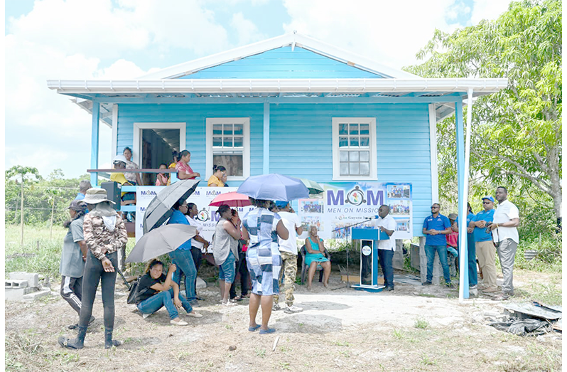 Minister McCoy addresses the small gathering outside the new house which was built through the MoM programme. Also pictured sitting on a chair is the recipient, 80-year-old Dalia Lewis (MoM photo)