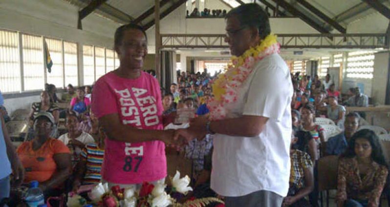 A parent receives her voucher from Labour Minister Dr Nanda Gopaul at Tagore Memorial