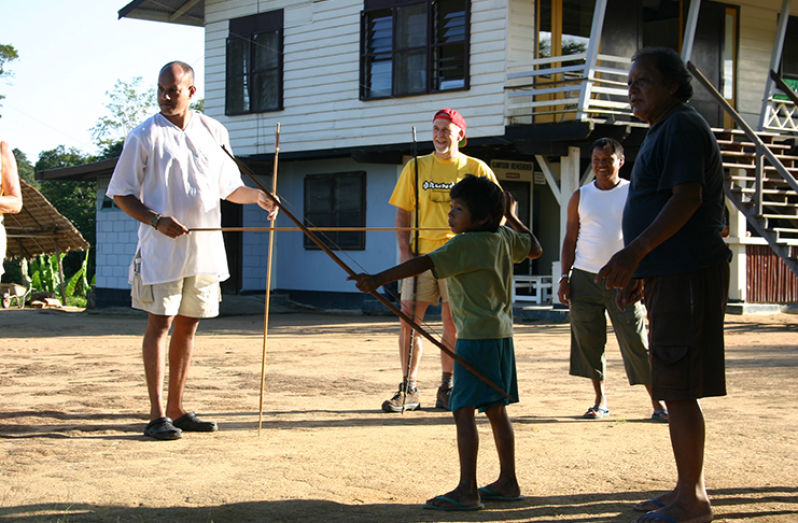 A young boy demonstrating to some visitors how to use the bow and arrow