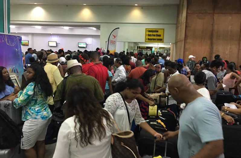 A crowd of people waiting to board their flight at the Cheddi Jagan airport on Saturday. (Trevor Benn photo)