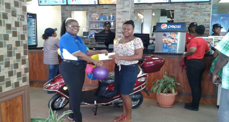 Director of Camex Restaurants Inc., Ms Dawn Braithwaite, hands over the keys of the scooter, first prize in the competition, to Niketa Cornelius.