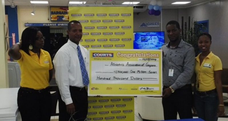 COURTS Marketing Manager, Pernell Cummings, hands over the sponsorship to president of the AAG, Aubrey Hutson, at the furniture giant’s Main Street store.