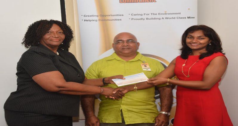 Guyana Goldfields Country Manager and Senior Vice- President, Ms. Violet Smith handing over the cheque to CUSO Caribbean Representative, Ms. Taramattie Persaud. At centre is Principal of the Linden Technical Institute, Mr. Denis Jaikarran