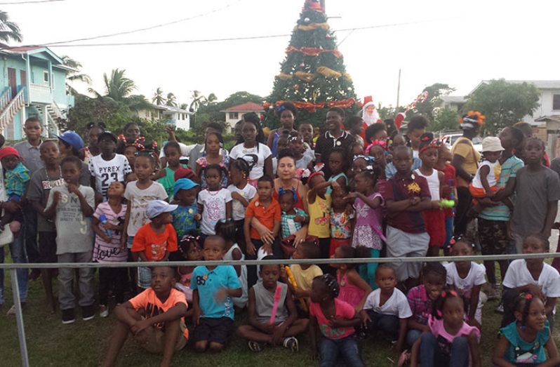 The Christmas tree stands majestically in the background, while the children wait for the light to be switched on