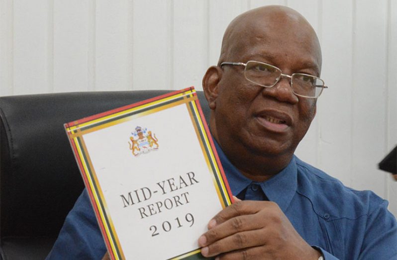 Finance Minister, Winston Jordan display a copy of the report during his presentation