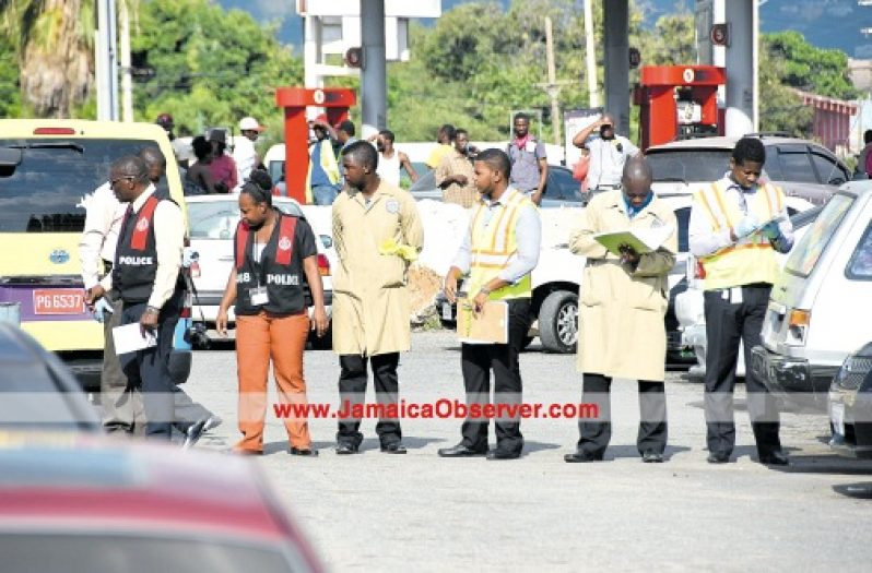 Crime scene investigators collect evidence on Marcus Garvey Drive, just outside of the Hunt’s Bay Police Station, following a shooting between the police and a gunman. (Photo: Lionel Rookwood)