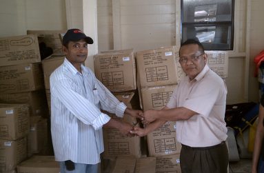 Sharir Chan handing over boxes of TOMS shoes to an official for Regions Seven and Eight