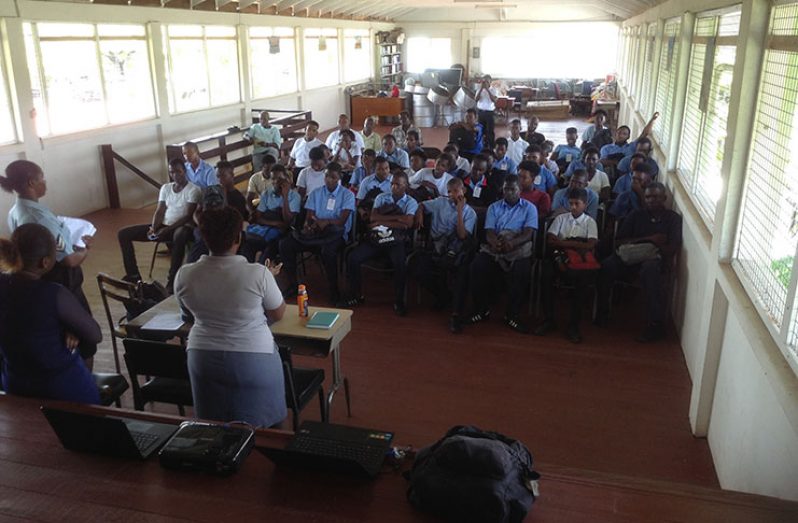Students being lectured by a member of the Guyana Police Force on the dangers of drug use