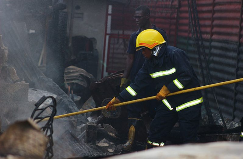 A fire-fighter uses a metal pole to demolish concrete remains at the Georgetown Prison compound on Camp St (Ravin Singh)
