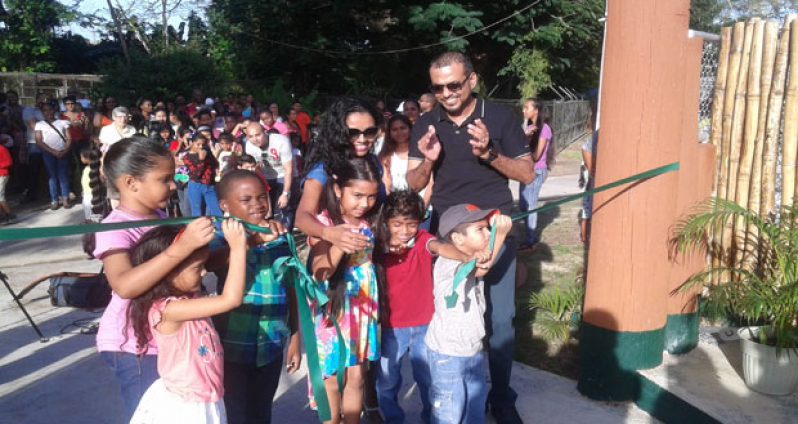 Some youngsters in the presence of Minister Persaud take part in cutting the ribbon to declare the petting zoo open