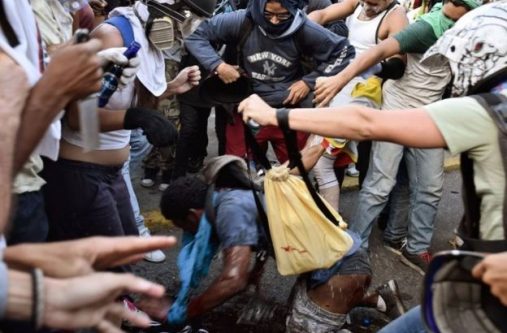 Photos showed a crowd of masked men surrounding Mr Figuera and dousing him with petrol