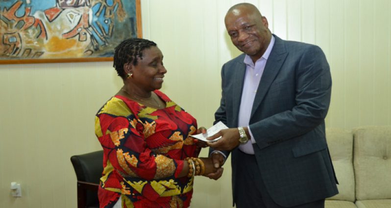 Minister of State Joseph Harmon handing over the cheque to ACDA volunteer Gail Napoleon, yesterday (Jules Gibson photo)