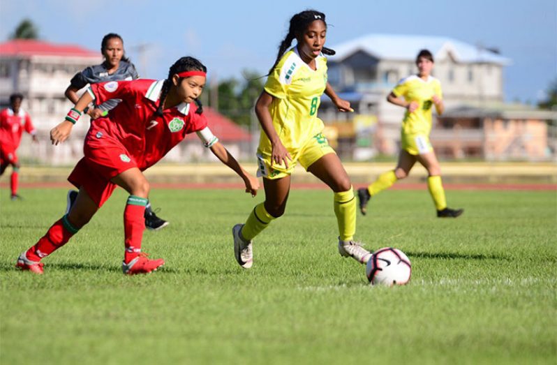 FLASHBACK! Lady Jags’ Serena McDonald (#8) dribbles by Suriname’s captain Cady Chin-See-Chong during Guyana’s 3-1 win at the National Track and Field Centre in 2019. (Samuel Maughn photo)