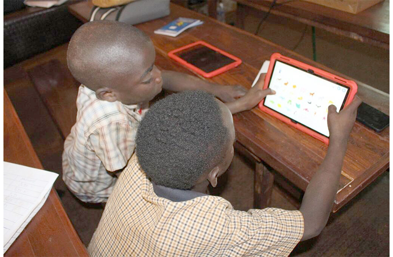 Two young boys work on a tablet in Tanzania (UNHCR/Maimuna Mtengela photo)