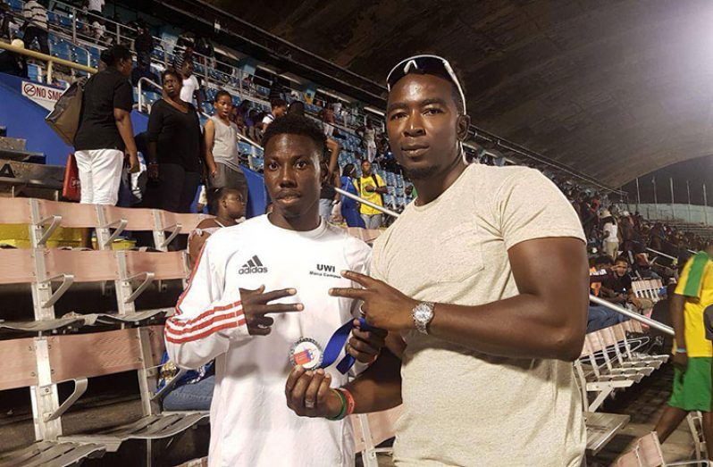 Guyana’s track and field star, Emanuel Archibald and his coach, Kerry Lee Ricketts after winning gold in the long jump on Saturday.
