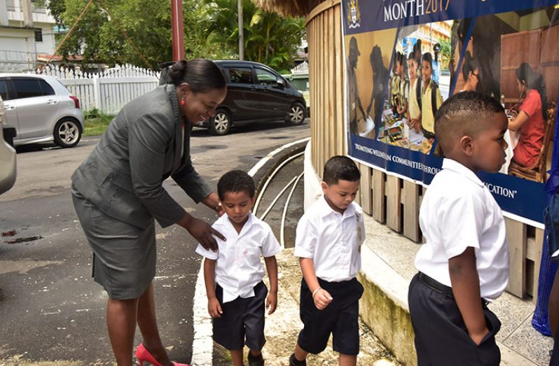Minister of Education, Ms Nicolette Henry, helping some youngsters make their way into the Umana Yama on Monday during the Launch of Education Month 2017