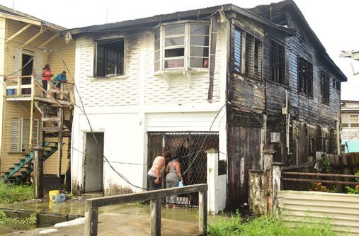 Sandra Christie (right) and a relative peer into the bottom flat of the gutted building, where Christie operates a hair salon (Adrian Narine photo)
