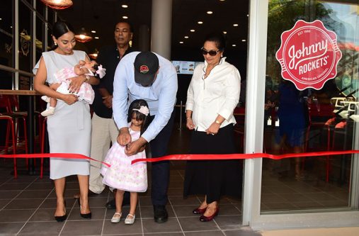 AN1_0156 Co-owner Ameir Ahmad with his daughter in the ribbon-cutting ceremony to declare the business open on Thursday while his wife, Preeta Mangar, her other daughter and relatives look on.