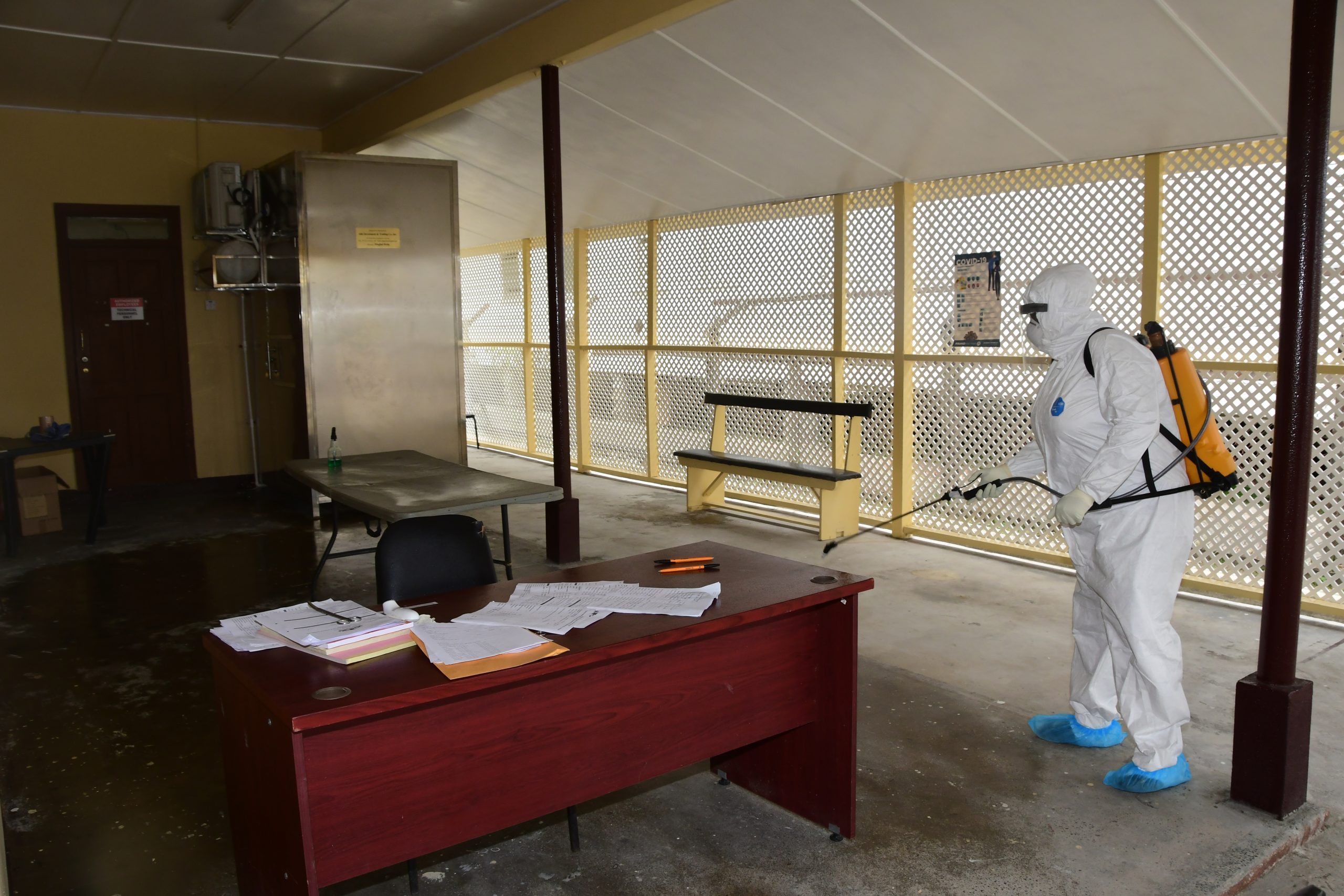 A health worker sanitizes a public building in April 2020. 

(Adrian Narine/Guyana Chronicle)