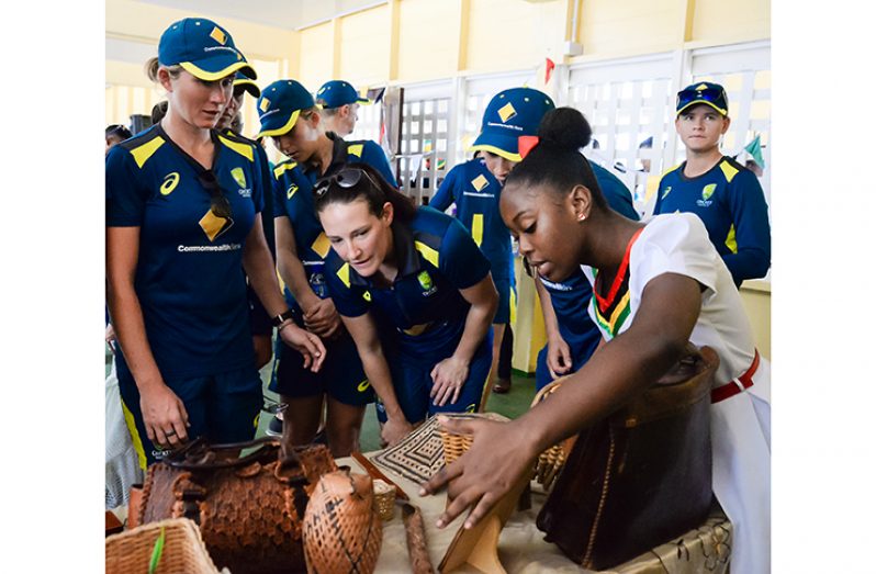 A student of East Ruimveldt Secondary grabs the attention of some of the ‘Aussie’ women as she displays some arts and craft made by students of the institution. (Delano Williams photo)