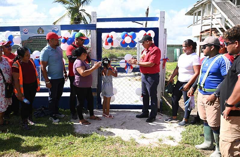 A student cuts the ribbon officially commissioning the new Well in Acquero Village in the Moruca Sub-region, Region One