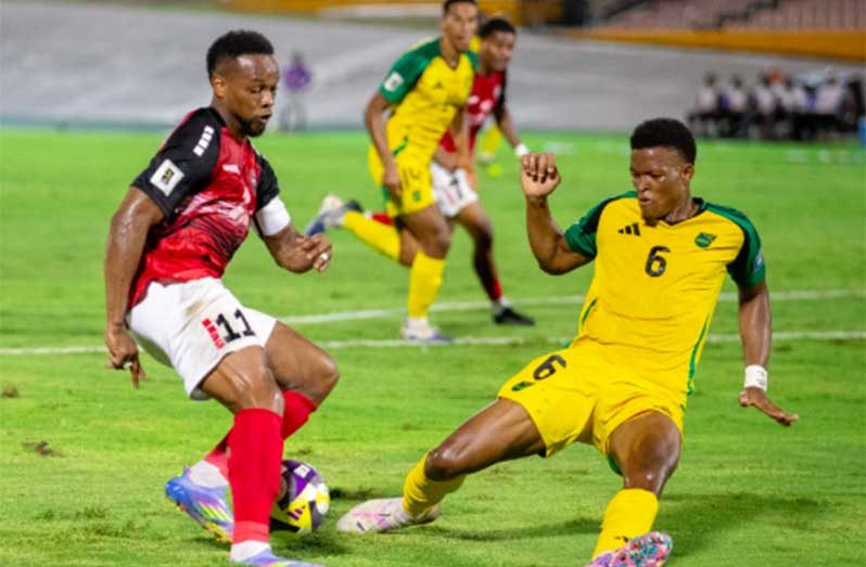 T&T’s Levi Garcia (l) gets by Reggae Boyz defender Richard King during their Concacaf World Cup Qualifier at the National Stadium in Kingston on Tuesday (Photo: Concacaf)