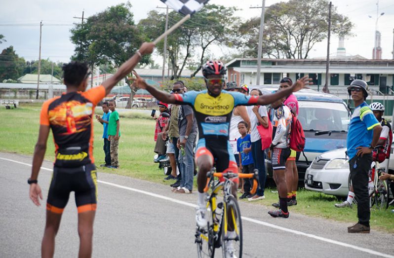Shaquille Agard raises his hands in jubilation as he crosses the finish line to win the Team Alanis 20-lap criterium around the outer circuit of the National Park yesterday (Delano Williams photo).