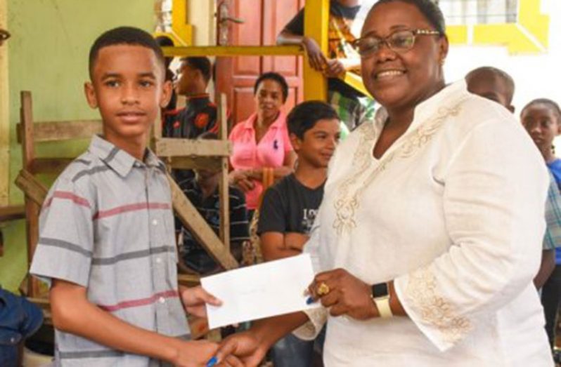 Aidan Allicock receiving his donation from Minister Broomes.