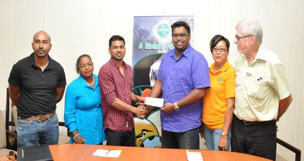 Competitor and club captain Danny Persaud collects the cheque from Minister of Tourism Irfaan Ali yesterday, while other officials of the GMR&SC look on.