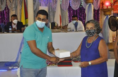 Widow of Mr Ananda E.T Dharry hands over cricket balls to Ameer Rahaman of the Rose Hall Canje CC.