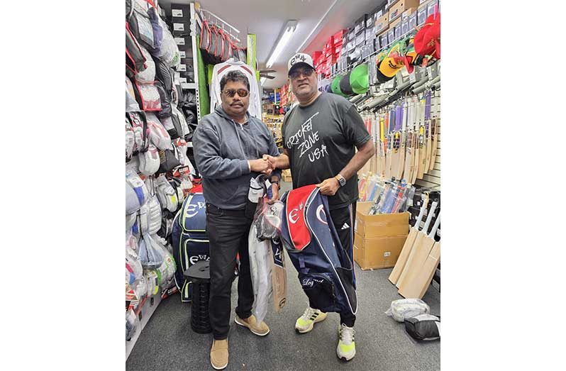 Anil Beharry left, receives part of the gear from  Ravi Etwaroo