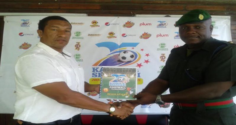 President of the Ann’s Grove Football Club, Major Raul Jerrick, collects the tournament’s rules and regulations handbook from organiser Kashif Mohammad of the K&S Organisation.