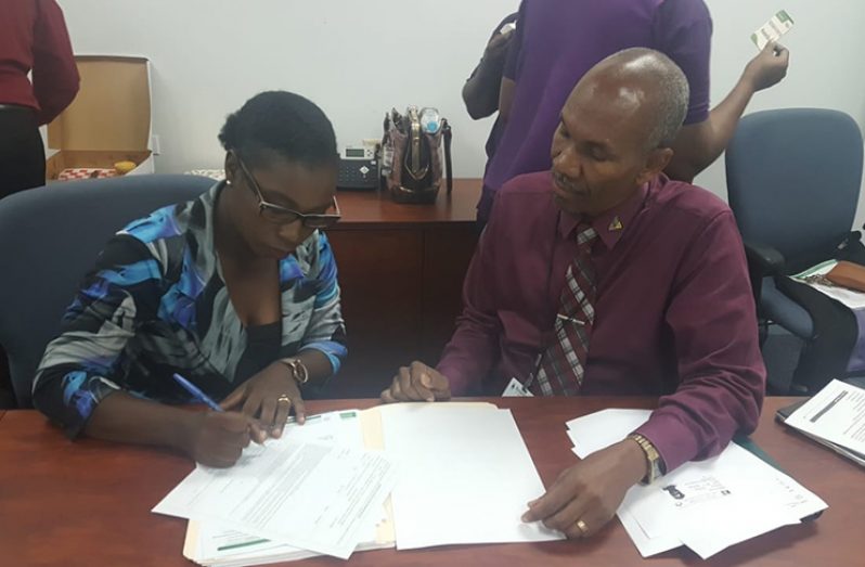 Nurse Nadine Saunders was the first GNA member to sign up for coverage under Assuria General Insurance. In this photo, she is signing in the presence of Assuria General Insurance Life Manager, Erwin Daniel.